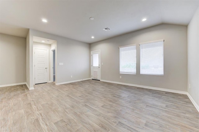 empty room featuring vaulted ceiling and light wood-type flooring