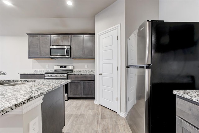 kitchen featuring sink, light hardwood / wood-style flooring, light stone counters, dark brown cabinetry, and stainless steel appliances