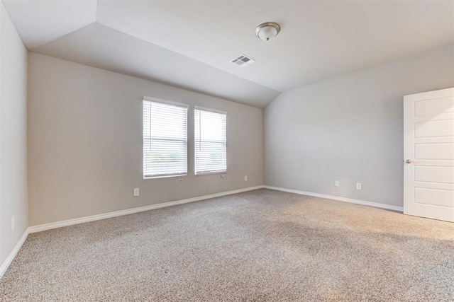 carpeted empty room featuring vaulted ceiling