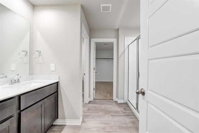 bathroom featuring hardwood / wood-style flooring, vanity, and walk in shower