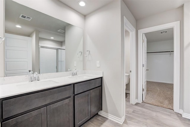 bathroom featuring hardwood / wood-style flooring, vanity, toilet, and a shower with shower door