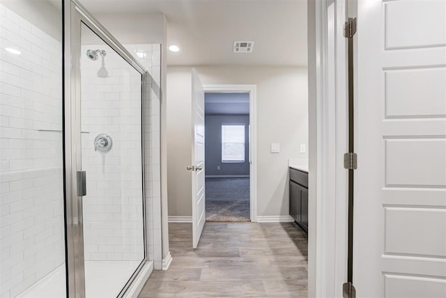 bathroom featuring hardwood / wood-style floors, vanity, and a shower with door