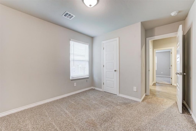 unfurnished bedroom with light carpet and a closet