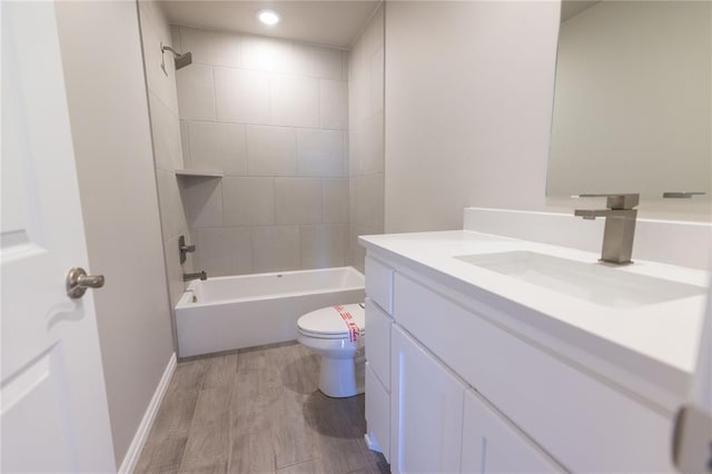 full bathroom with hardwood / wood-style flooring, vanity, tiled shower / bath combo, and toilet