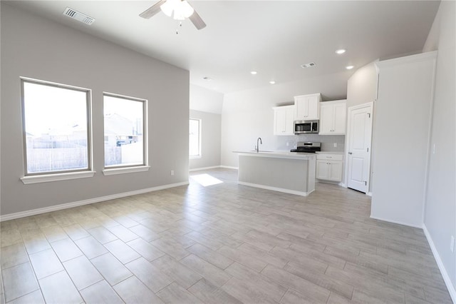 unfurnished living room featuring ceiling fan, sink, and light wood-type flooring