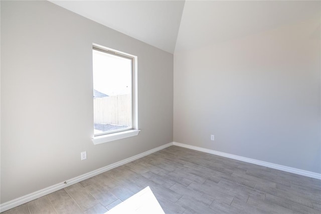 spare room with vaulted ceiling and light hardwood / wood-style floors