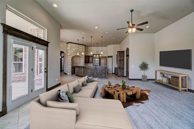 living room with ceiling fan, light tile patterned flooring, and a towering ceiling