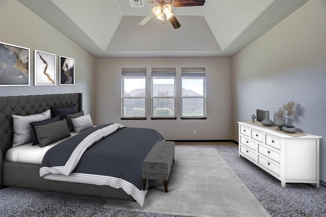 bedroom with a raised ceiling, light carpet, and ceiling fan