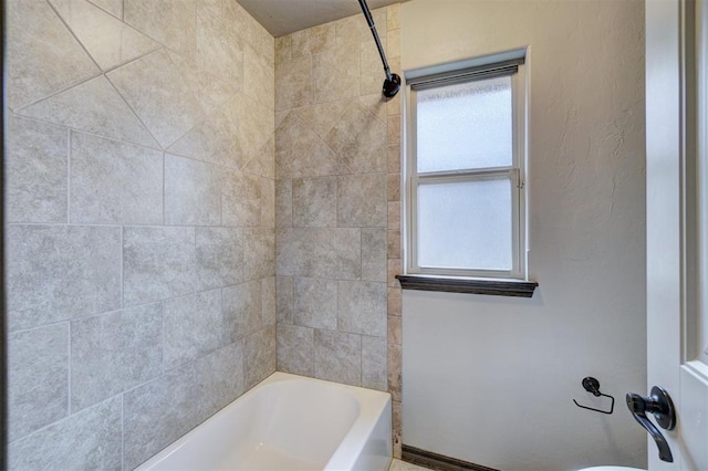 bathroom featuring tiled shower / bath combo and toilet