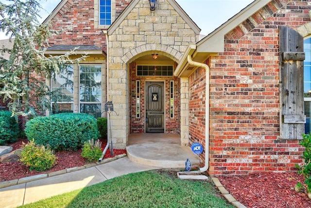 doorway to property featuring stone siding and brick siding