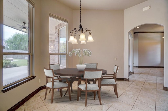 dining room with arched walkways, ceiling fan, baseboards, and light tile patterned floors