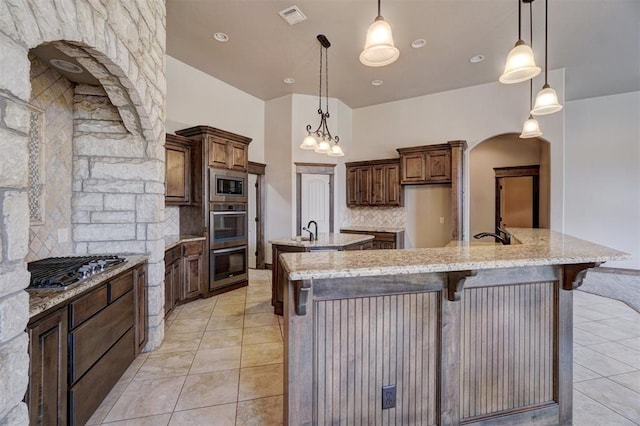 kitchen with appliances with stainless steel finishes, visible vents, decorative light fixtures, and a large island