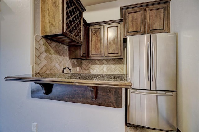 kitchen with backsplash, freestanding refrigerator, and dark brown cabinetry