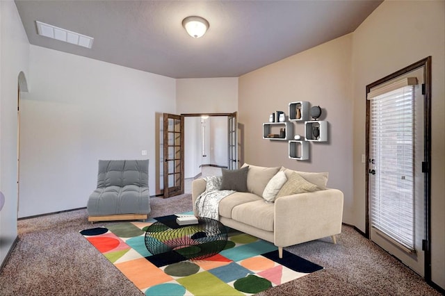 carpeted living room featuring arched walkways, french doors, and visible vents