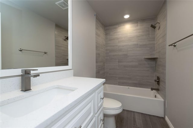 full bathroom with tiled shower / bath, vanity, and toilet