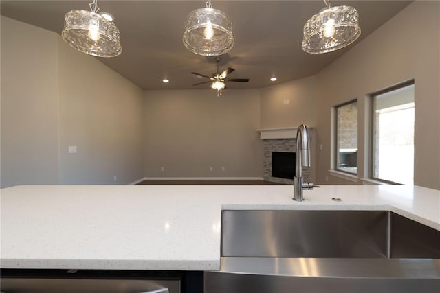 kitchen with a stone fireplace, ceiling fan, and sink