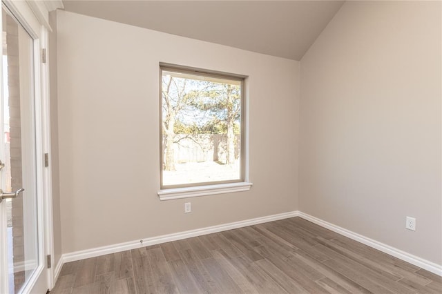 empty room featuring hardwood / wood-style flooring, vaulted ceiling, and a healthy amount of sunlight