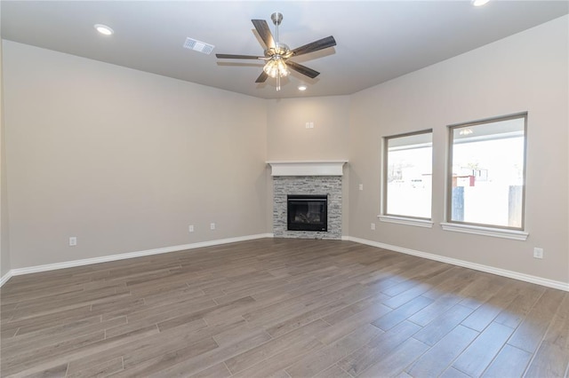 unfurnished living room featuring a stone fireplace, ceiling fan, and light wood-type flooring