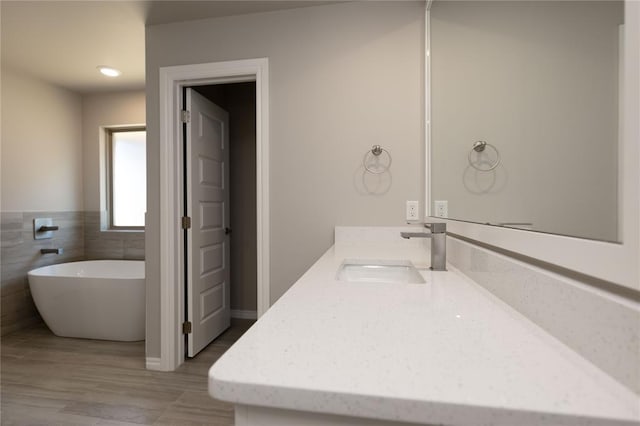 bathroom with vanity, a bathtub, and tile walls