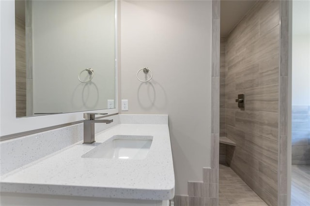 bathroom featuring tiled shower and vanity