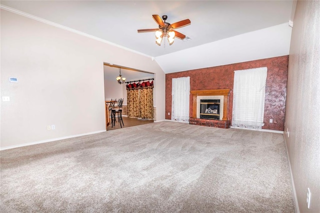 unfurnished living room with ceiling fan with notable chandelier, carpet floors, ornamental molding, and vaulted ceiling