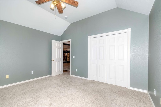 unfurnished bedroom featuring ceiling fan, a closet, light carpet, and vaulted ceiling