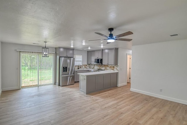 kitchen with gray cabinetry, stainless steel appliances, ceiling fan, pendant lighting, and light hardwood / wood-style flooring