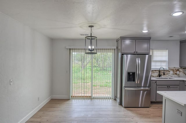 kitchen featuring gray cabinetry, stainless steel fridge with ice dispenser, sink, and plenty of natural light