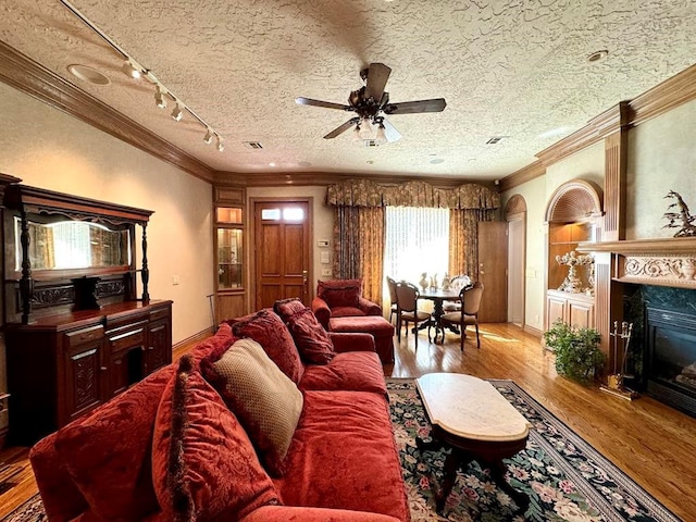 living room featuring a textured ceiling, light hardwood / wood-style floors, ceiling fan, and crown molding