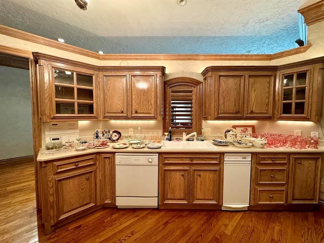 kitchen featuring white dishwasher, sink, crown molding, a textured ceiling, and dark hardwood / wood-style flooring