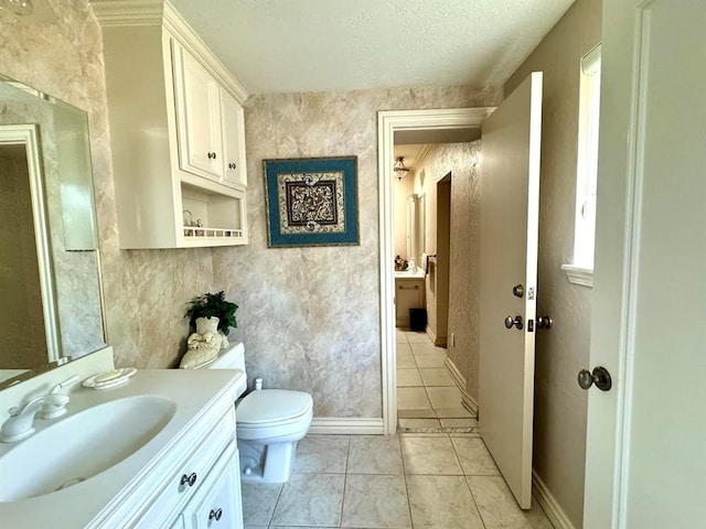 bathroom with tile patterned floors, vanity, toilet, and a textured ceiling