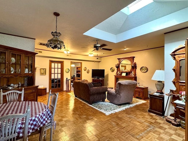 living room featuring a skylight, ceiling fan, light parquet flooring, and a textured ceiling