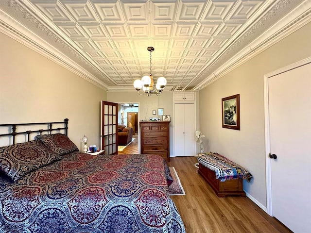 bedroom featuring a chandelier, ornamental molding, and hardwood / wood-style flooring