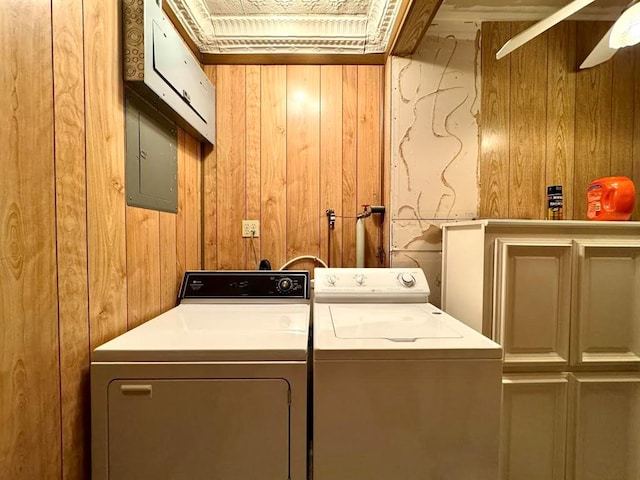 washroom with electric panel, cabinets, wooden walls, and washing machine and clothes dryer