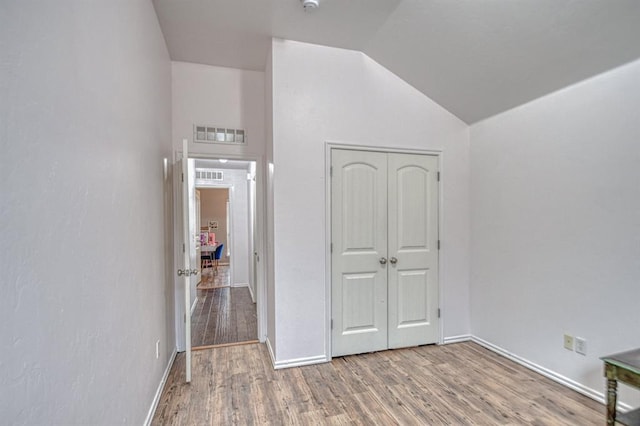 unfurnished bedroom featuring vaulted ceiling, hardwood / wood-style floors, and a closet