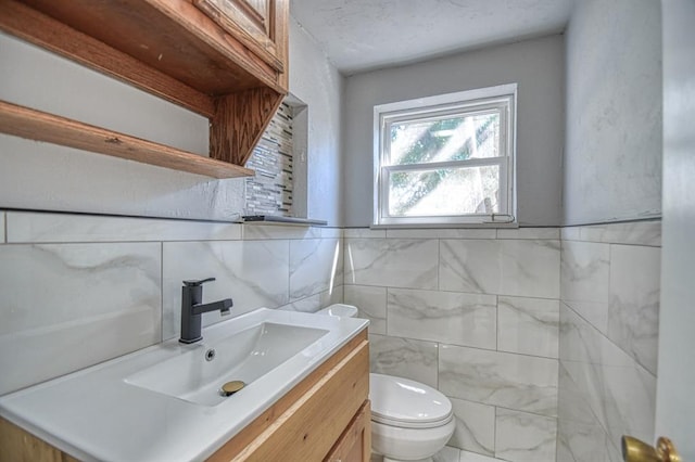 bathroom with vanity, toilet, and tile walls