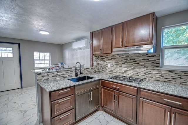 kitchen featuring kitchen peninsula, decorative backsplash, sink, and a wall mounted air conditioner