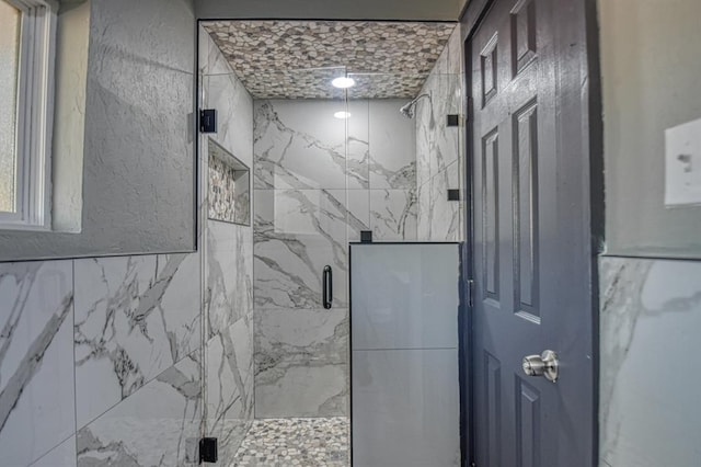 bathroom featuring a shower with door and tile walls