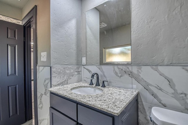 bathroom featuring vanity, tile walls, and toilet