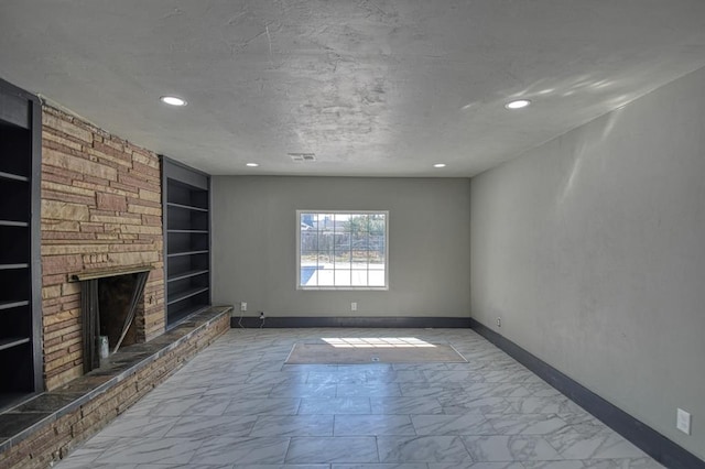 unfurnished living room with built in shelves, a stone fireplace, and a textured ceiling