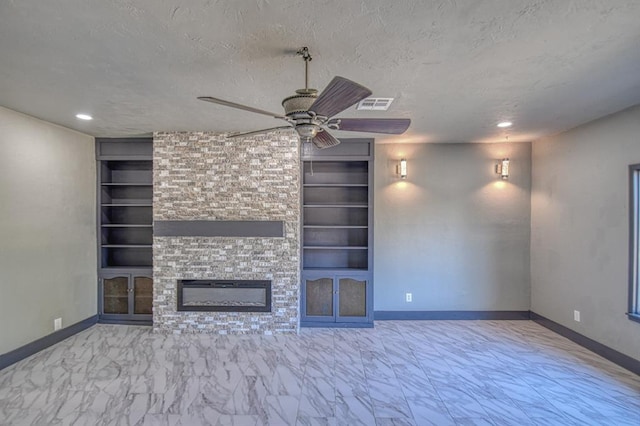 unfurnished living room featuring a textured ceiling, a large fireplace, built in features, and ceiling fan