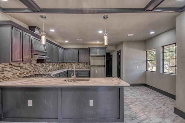 kitchen featuring tasteful backsplash, kitchen peninsula, sink, and hanging light fixtures