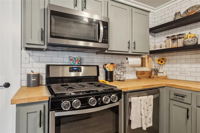 kitchen with tasteful backsplash, stainless steel appliances, and wood counters