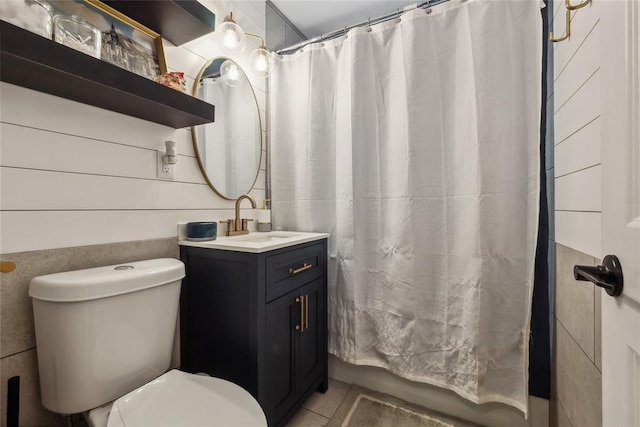 bathroom with tile patterned floors, vanity, toilet, and tile walls