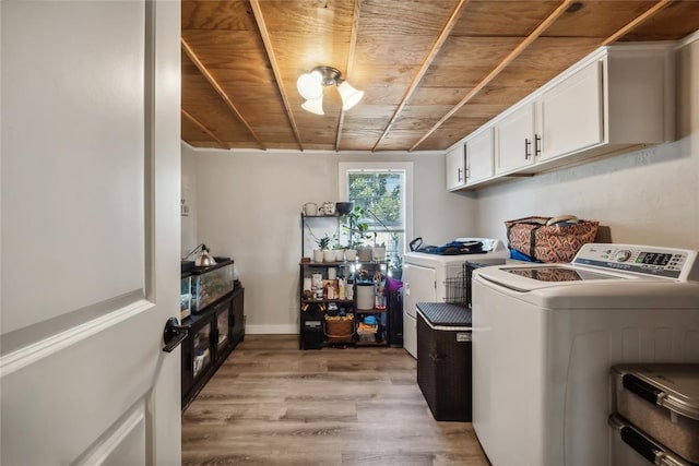 laundry room with wood ceiling, washer and dryer, light hardwood / wood-style flooring, and cabinets