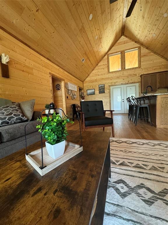 living room with wood walls, high vaulted ceiling, hardwood / wood-style flooring, ceiling fan, and wood ceiling