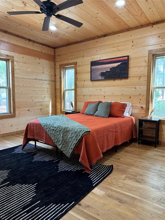 bedroom with ceiling fan, wood-type flooring, wood ceiling, and multiple windows