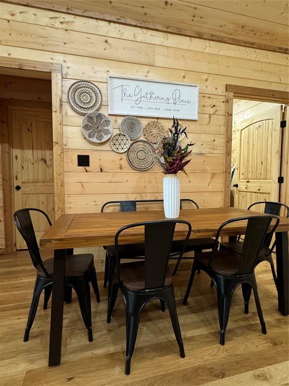 dining area with wood walls and light wood-type flooring