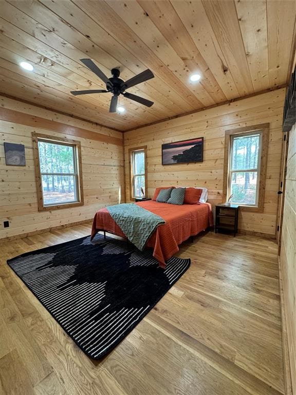 bedroom featuring hardwood / wood-style floors, multiple windows, and wood walls