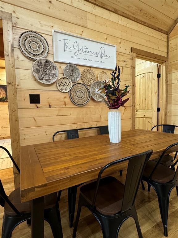 dining space with wooden walls and vaulted ceiling